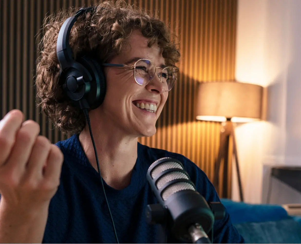 Woman smiling and speaking into a microphone, wearing headphones.