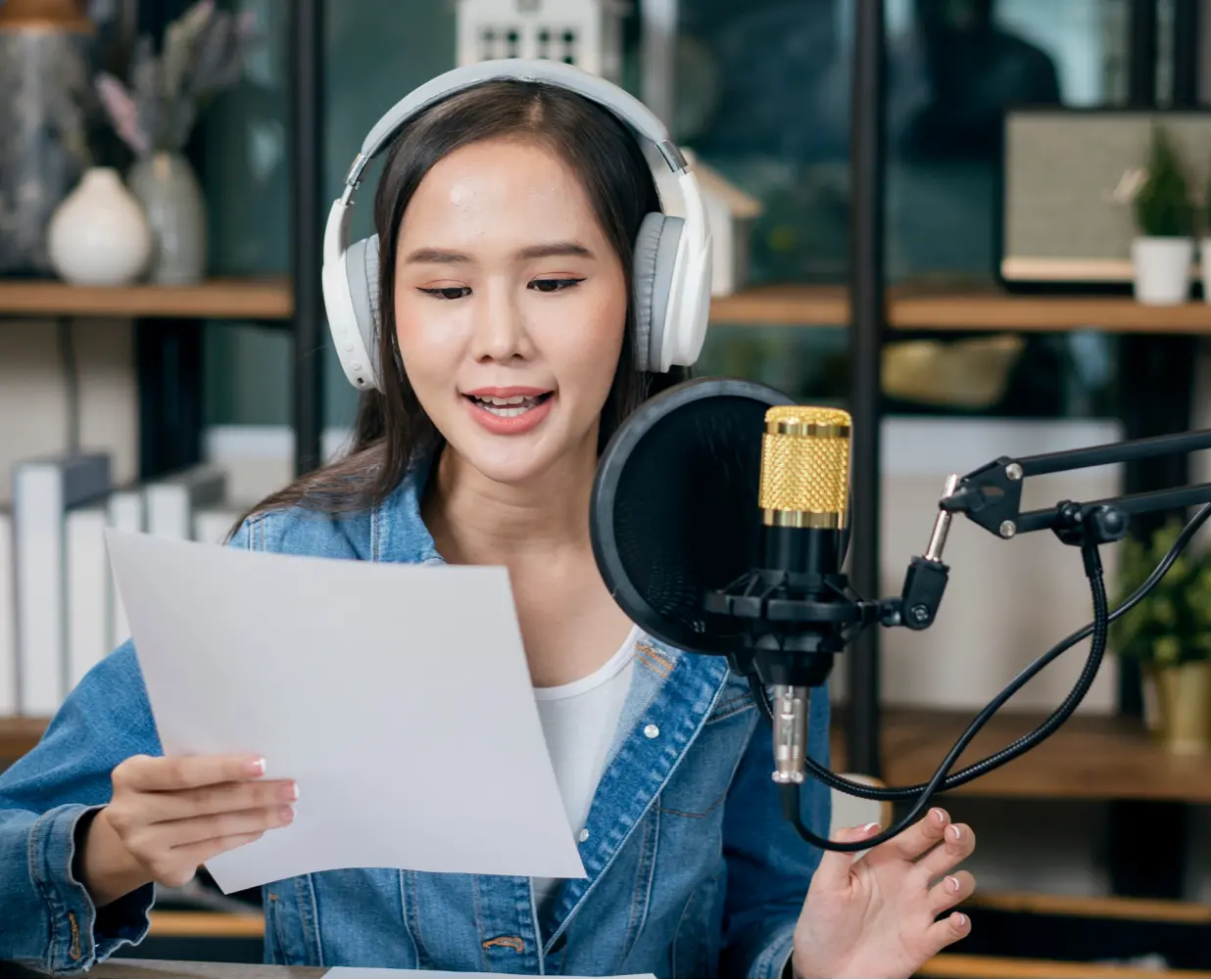 Woman speaking into a microphone, wearing headphones.